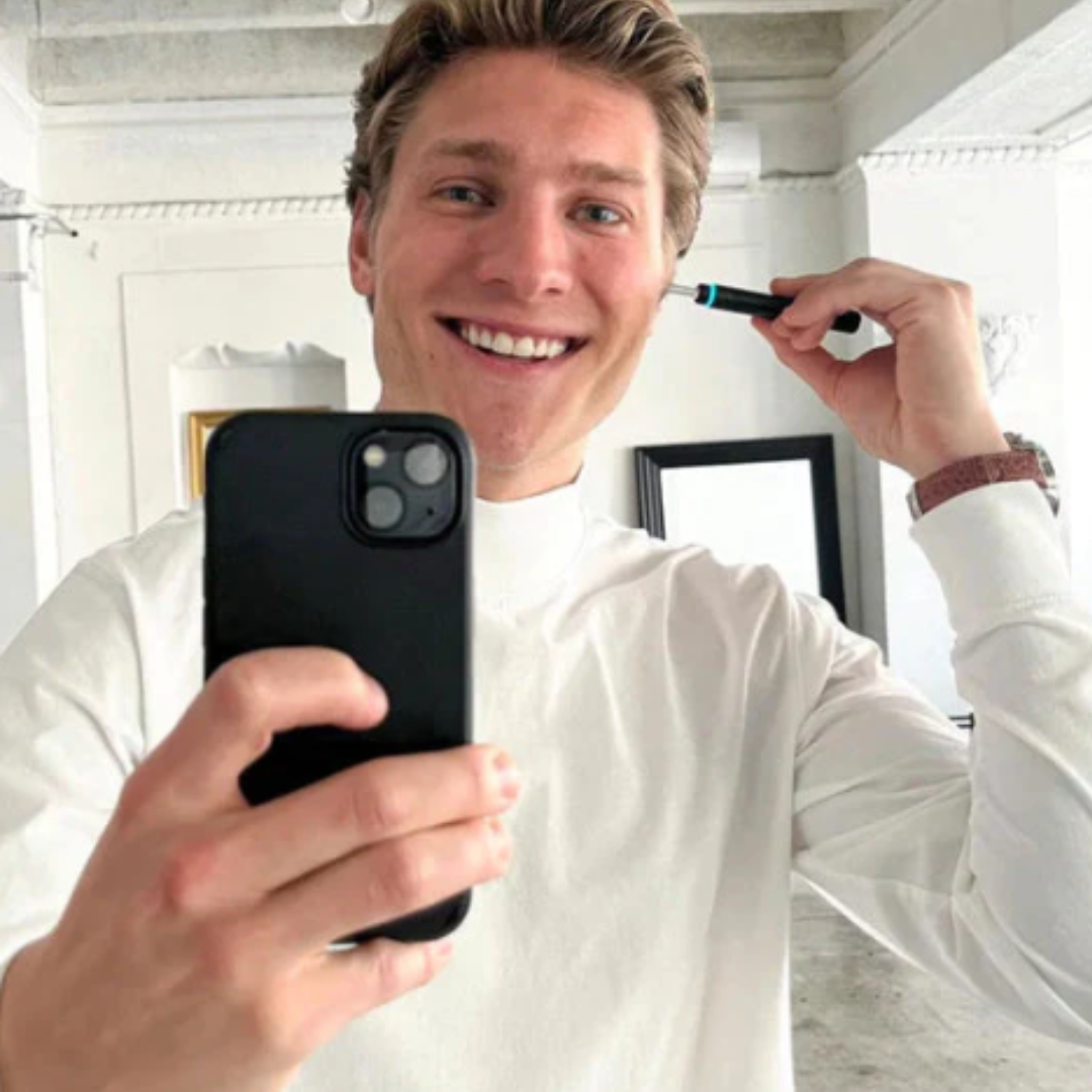 Person använder WaxClean öronvaxrengörare med HD-kamera och ser realtidsbild av hörselgången via smartphone.